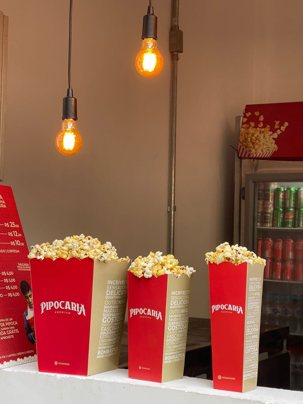 Embalagens Pipocaria Premium recém-cheias sob lâmpadas Edison
