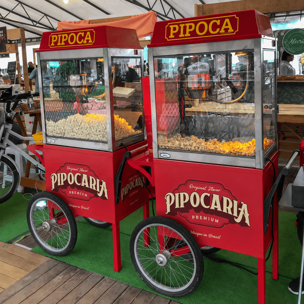 Dois carrinhos Pipocaria Premium lado a lado com máquinas de pipoca PIPOCA, em ambiente de festival