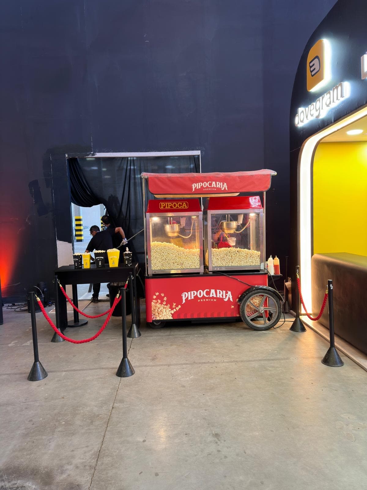 Carrinho Pipocaria Premium em evento, atendente operando, isolamento de fila