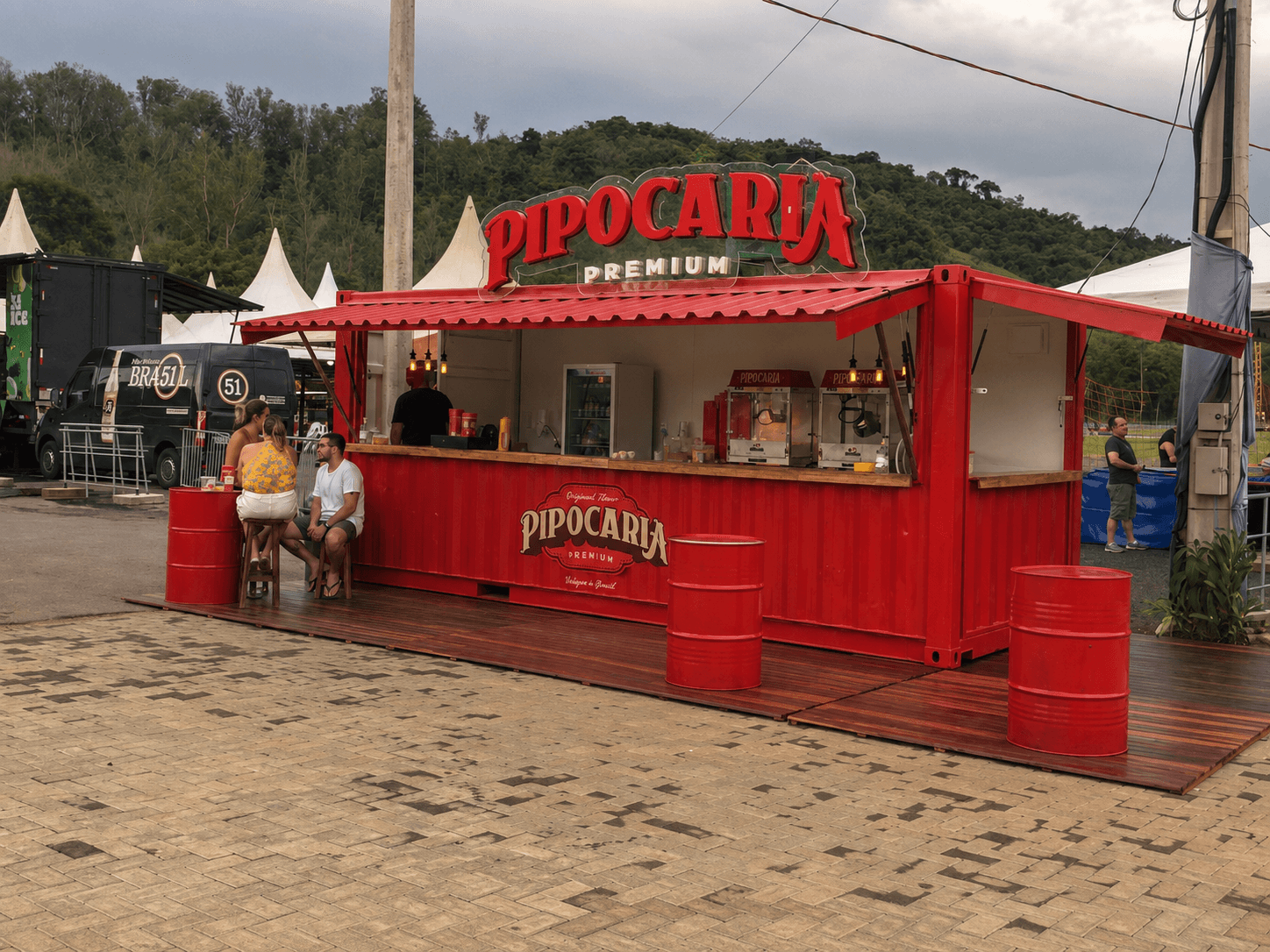 Container Pipocaria Premium 20 pés em festival outdoor com clientes no balcão e tendas atrás